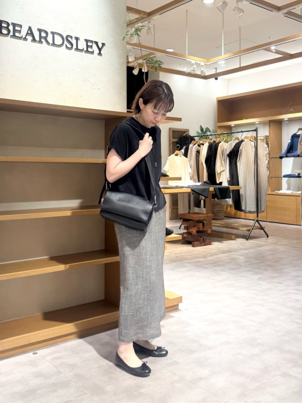 ブラック系のショルダーバッグ、ベージュ系のスカート、ゴールド系のネックレスを着用したレディースの春コーディネートの4枚目の写真