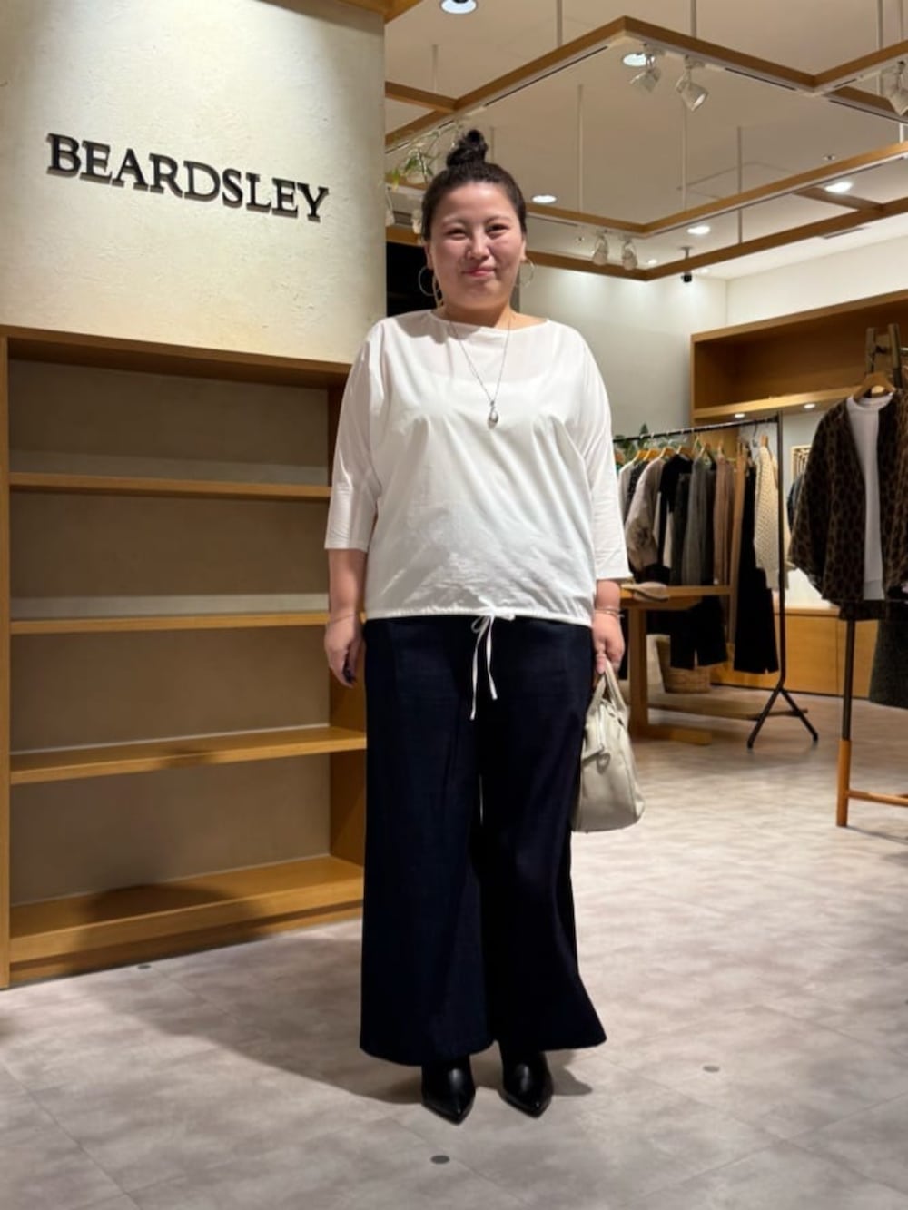 グレー系のボストンバッグ、ブラック系のブーツ、ホワイト系のシャツ/ブラウスを着用したレディースの冬コーディネートの2枚目の写真