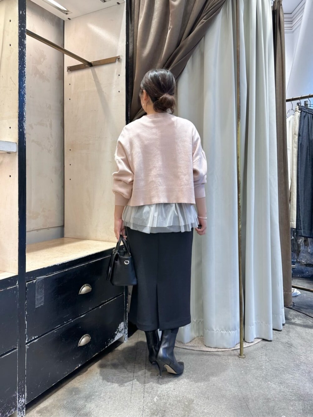 ブラック系のスカート、ブラック系のブーツ、ホワイト系のタンクトップを着用したレディースの冬コーディネートの3枚目の写真