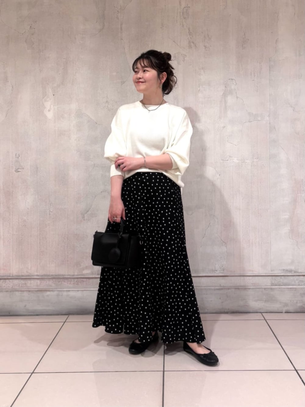 ブラック系のハンドバッグ、ブラック系のスカート、ホワイト系のTシャツ/カットソーを着用したレディースの春コーディネートの2枚目の写真