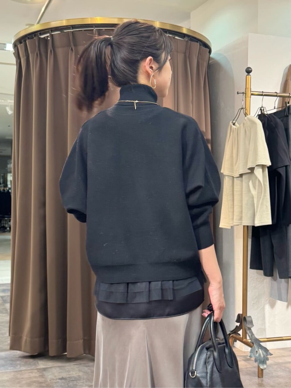 グリーン系のスカート、ブラック系のボストンバッグ、ブラック系のニット/セーターを着用したレディースの冬コーディネートの6枚目の写真