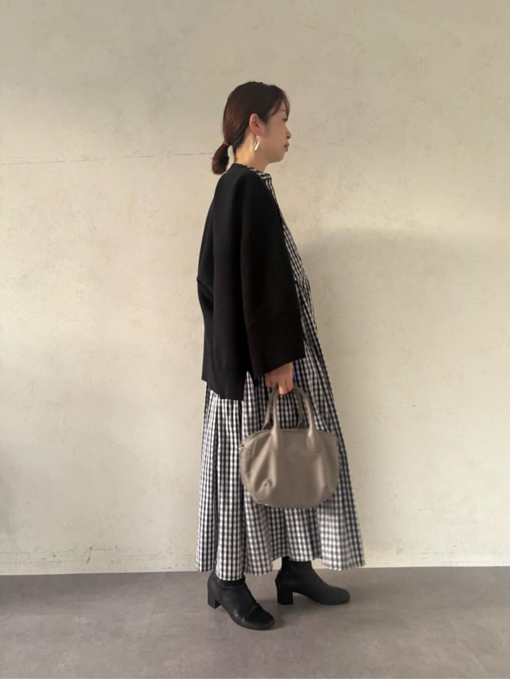 グレー系のボストンバッグ、ブラック系のカーディガン/ボレロ、ブラック系のワンピースを着用したレディースの冬コーディネートの3枚目の写真