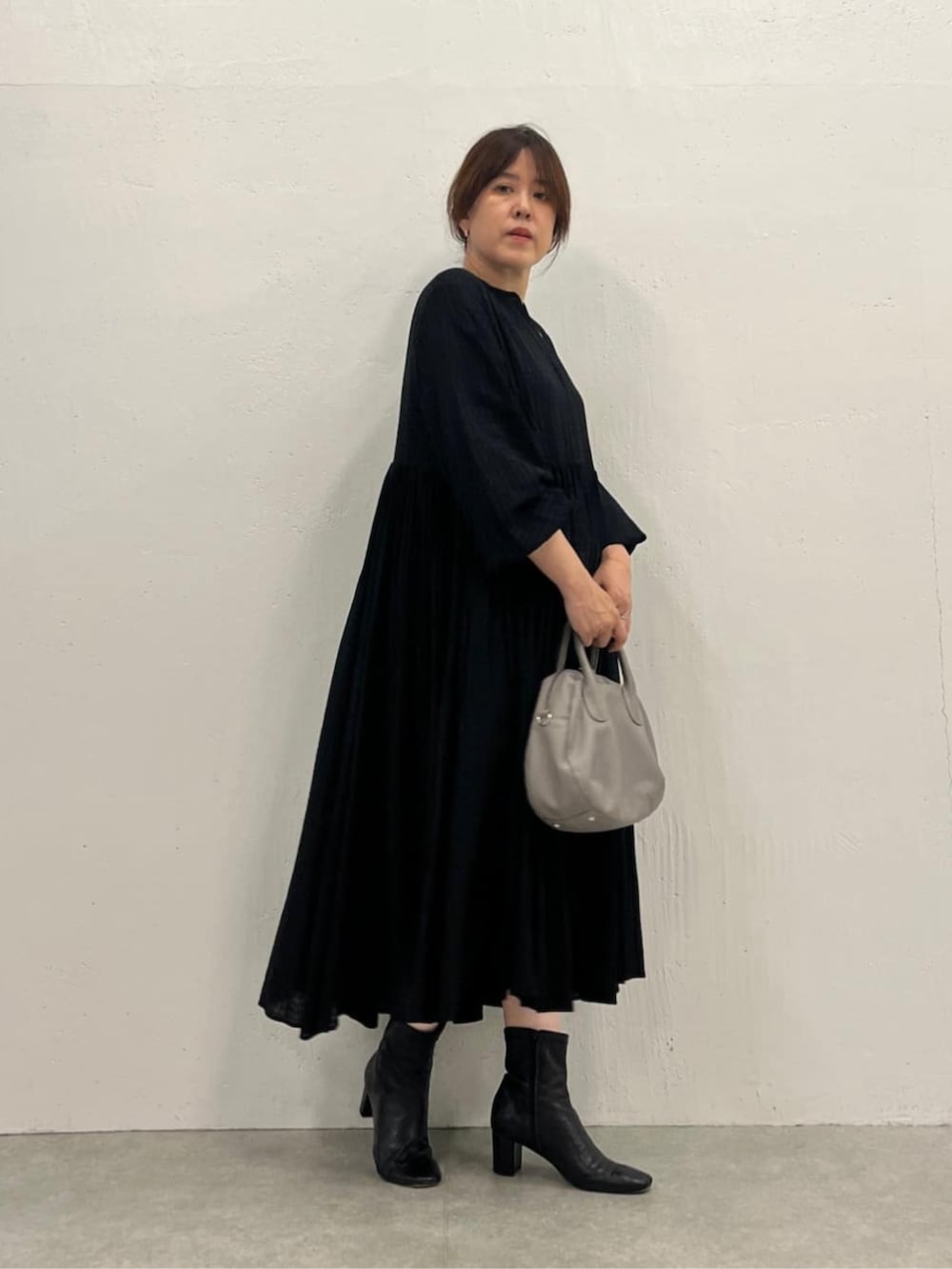 グレー系のボストンバッグ、ブラック系のワンピースを着用したレディースの夏コーディネートの2枚目の写真