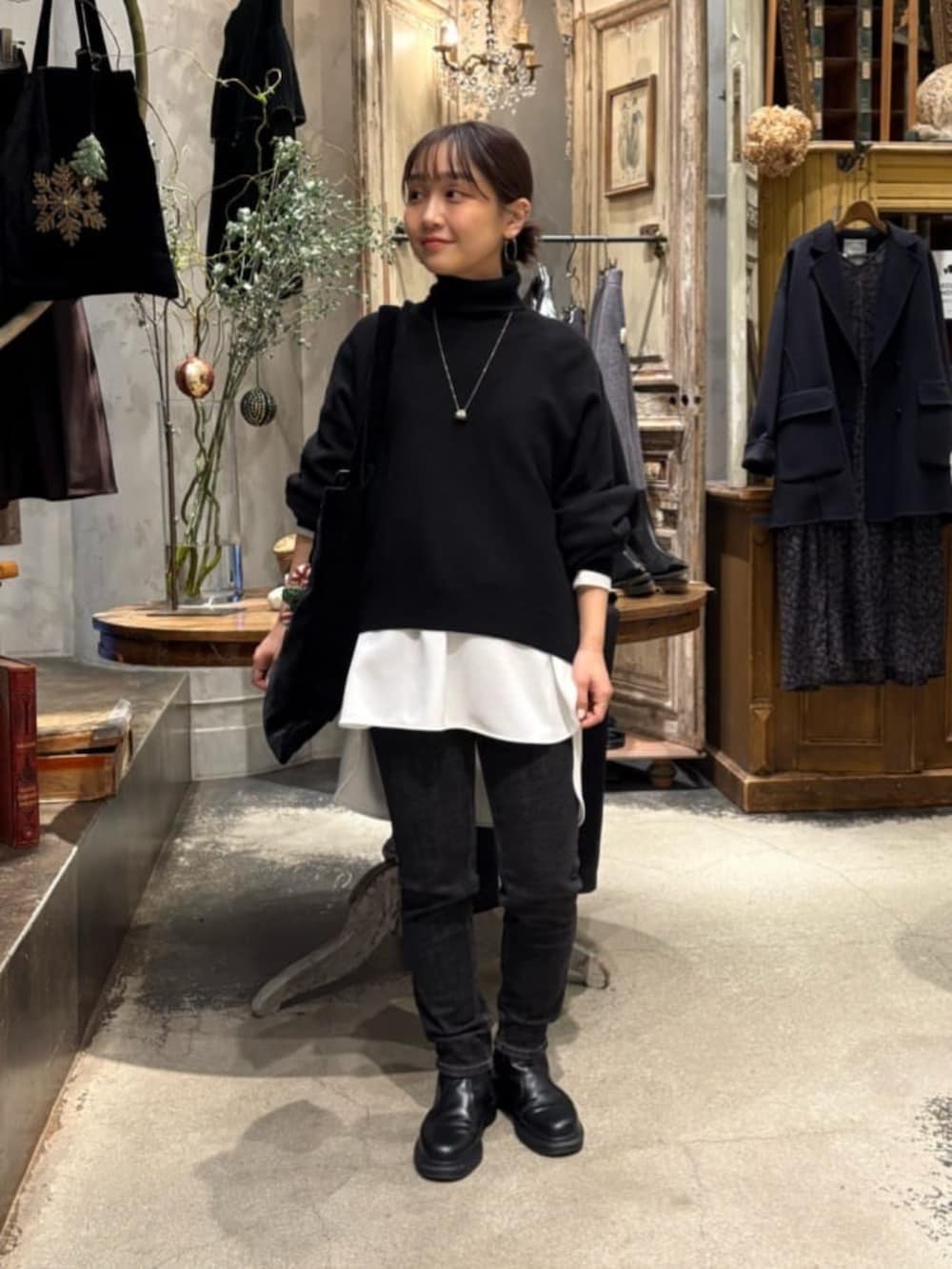 ブラック系のニット/セーター、ブラック系のデニムパンツ、ホワイト系のシャツ/ブラウスを着用したレディースの冬コーディネートの2枚目の写真