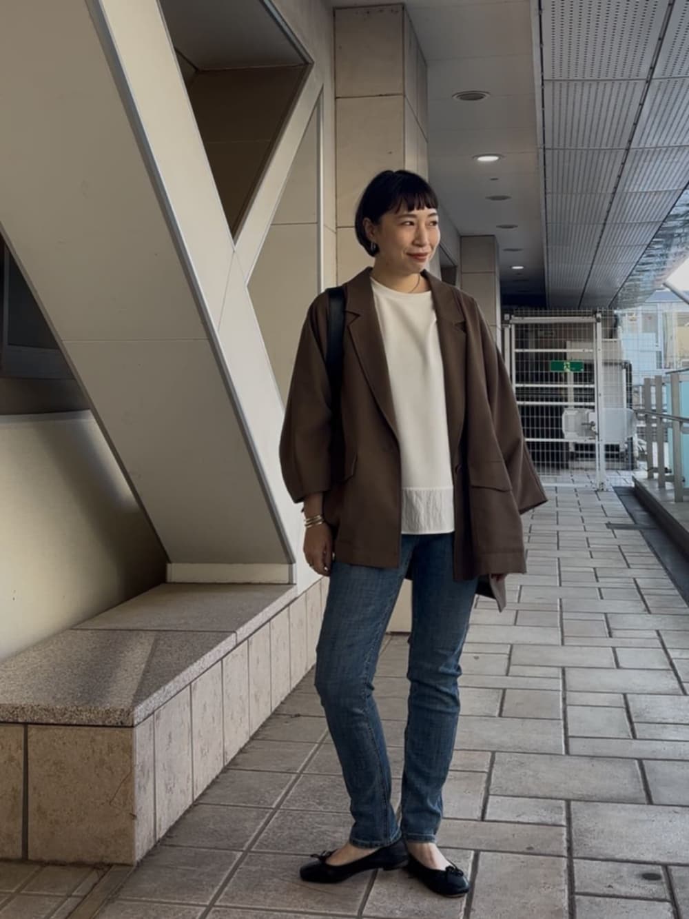 ブルー系のデニムパンツ、ブラウン系のテーラードジャケット、ホワイト系のTシャツ/カットソーを着用したレディースの春コーディネートの2枚目の写真
