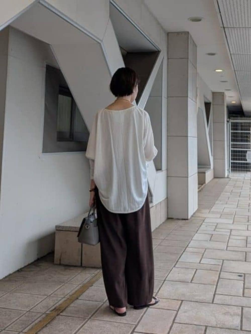 グレー系のハンドバッグ、ホワイト系のTシャツ/カットソー、ブラウン系のその他パンツを着用したレディースの夏コーディネートの3枚目の写真