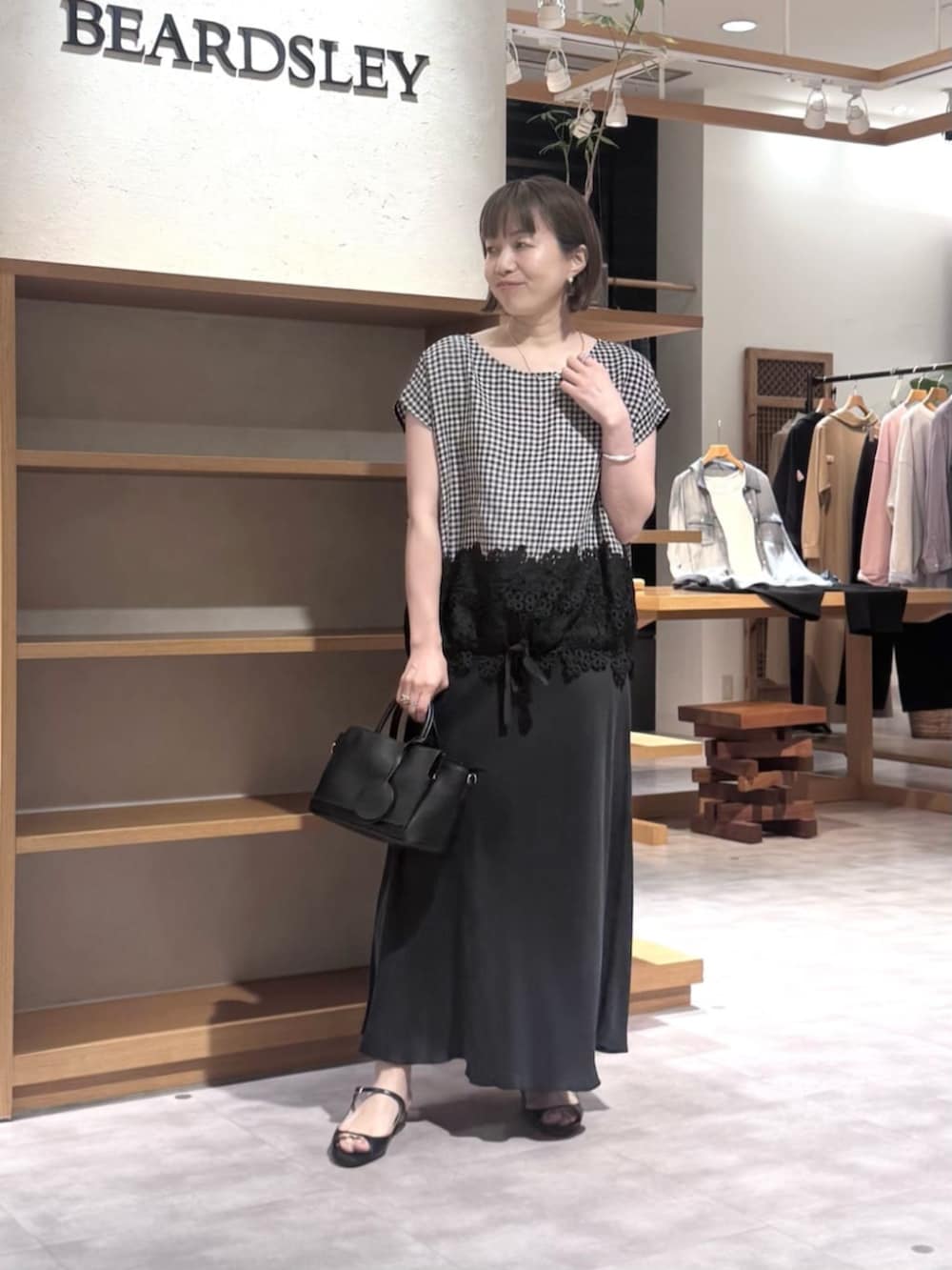 ブラック系のスカート、ブラック系のハンドバッグ、ブラック系のシャツ/ブラウスを着用したレディースの春コーディネートの2枚目の写真