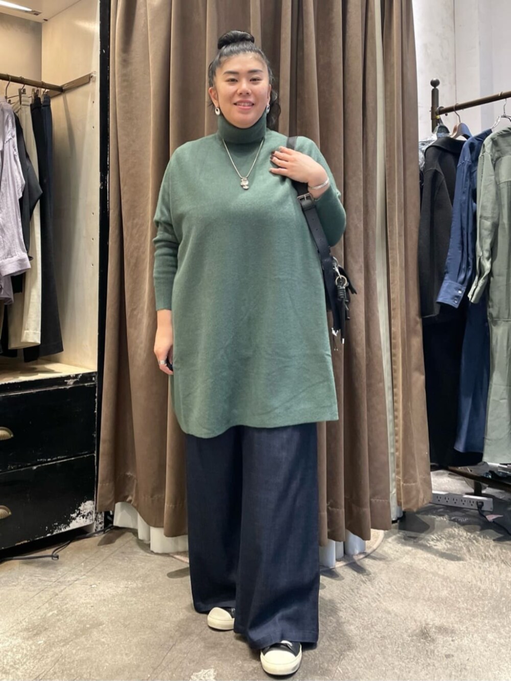 ブラック系のショルダーバッグ、ブラック系のその他アウター、グリーン系のニット/セーターを着用したレディースの冬コーディネートの6枚目の写真