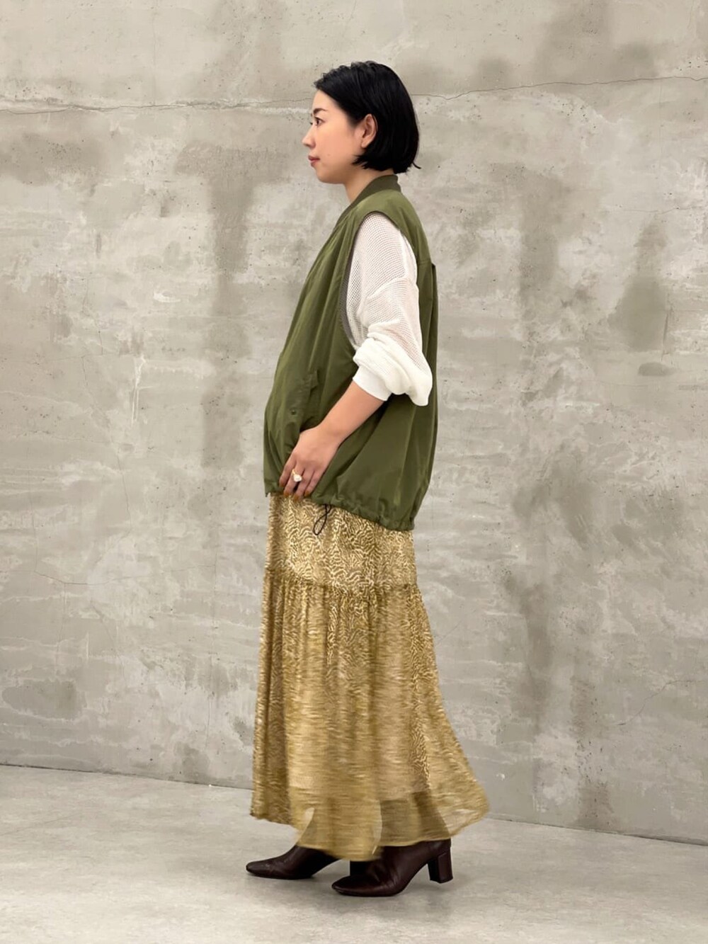 ホワイト系のTシャツ/カットソー、グリーン系のベスト、ベージュ系のスカートを着用したレディースの夏コーディネートの2枚目の写真