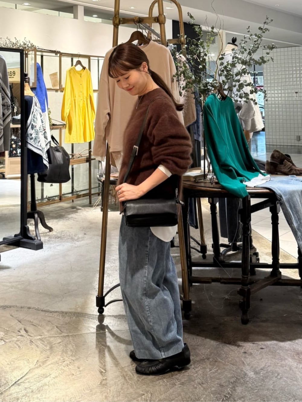 ブラック系のショルダーバッグ、ブラウン系のニット/セーター、ブルー系のその他パンツを着用したレディースの秋コーディネートの2枚目の写真