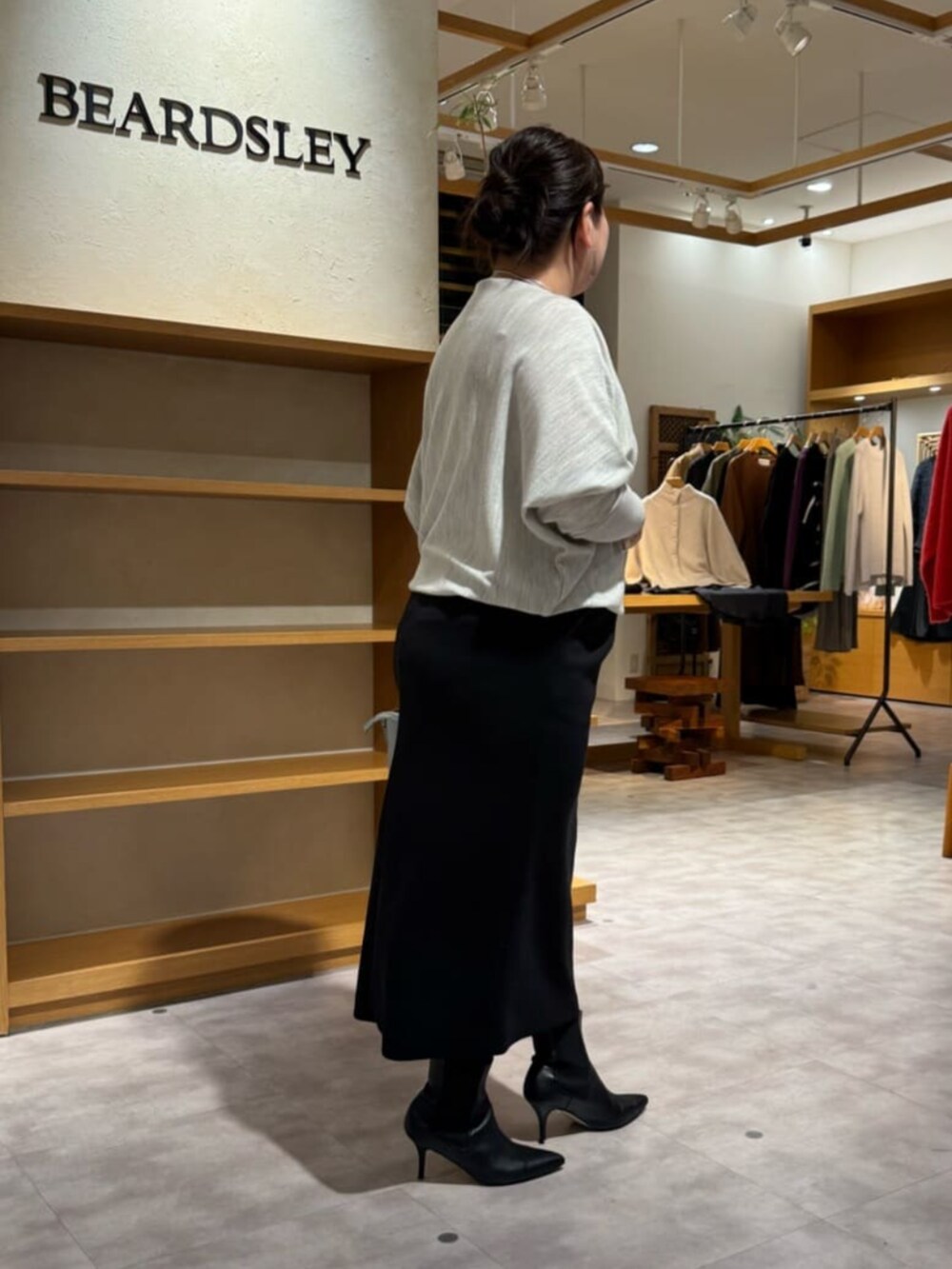 グリーン系のハンドバッグ、グレー系のニット/セーター、ブラック系のブーツを着用したレディースの冬コーディネートの5枚目の写真