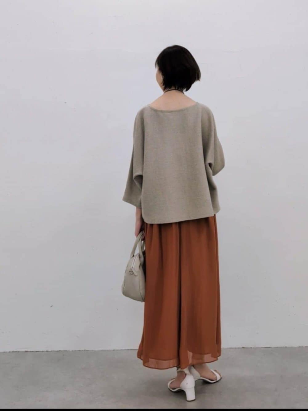 グレー系のボストンバッグ、オレンジ系のその他パンツ、ベージュ系のニット/セーターを着用したレディースの冬コーディネートの4枚目の写真