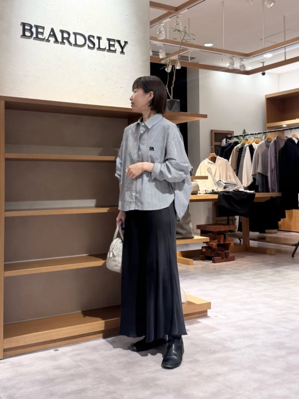 ブラック系のスカート、グレー系のボストンバッグ、ブルー系のシャツ/ブラウスを着用したレディースの冬コーディネートの2枚目の写真