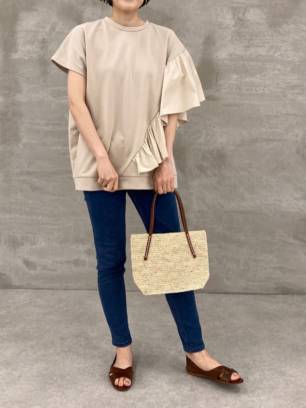 ベージュ系のTシャツ/カットソー、ブルー系のデニムパンツ、ホワイト系のかごバッグを着用したレディースの春コーディネートの2枚目の写真