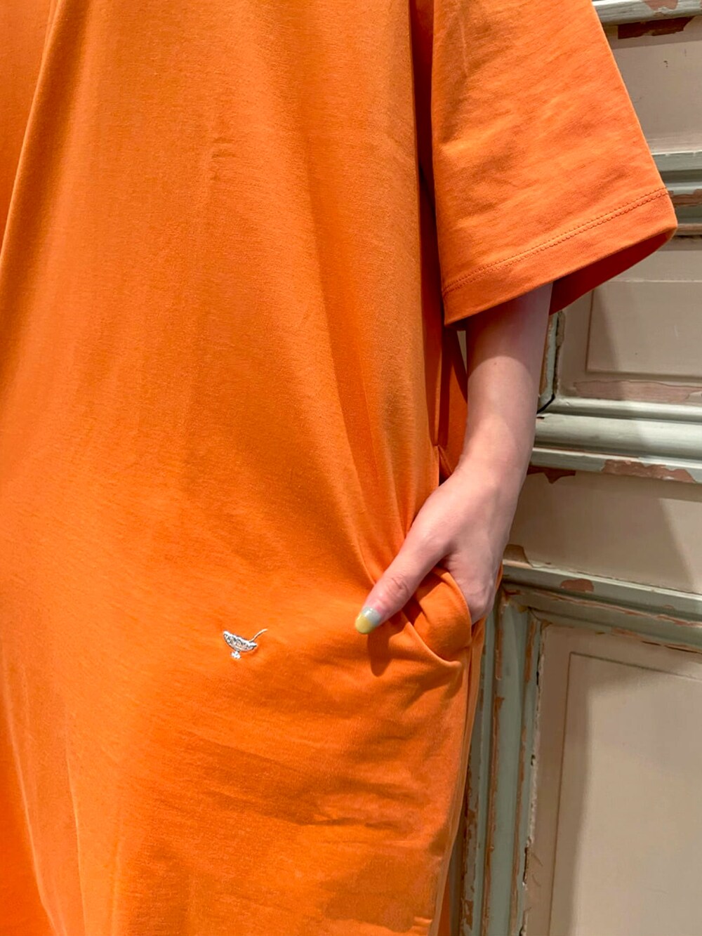 オレンジ系のTシャツ/カットソー、ホワイト系のかごバッグ、ホワイト系のサンダルを着用したレディースの春コーディネートの4枚目の写真