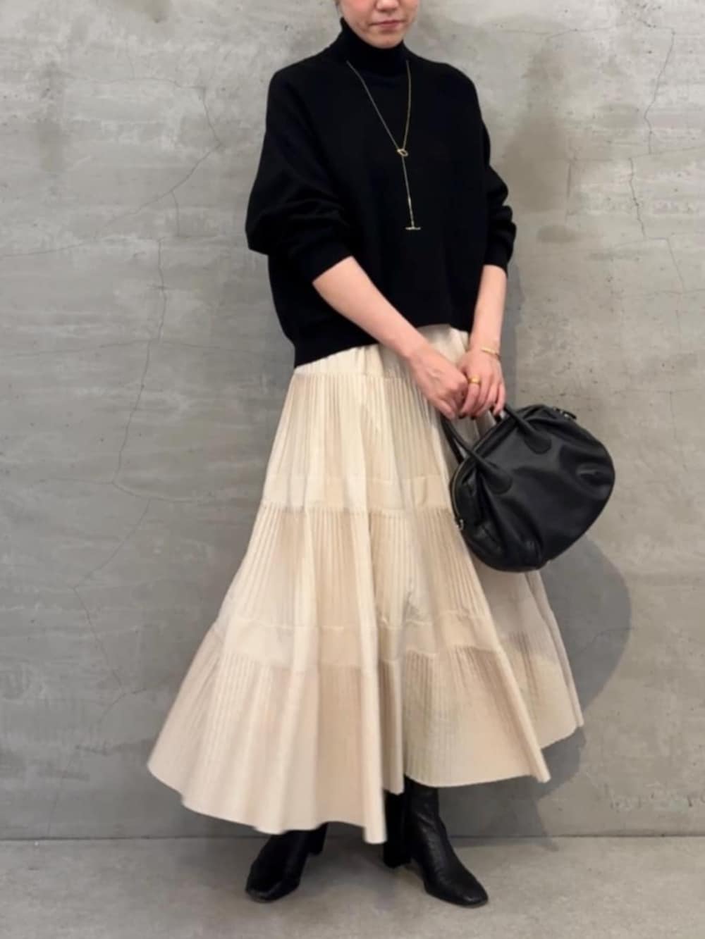 ホワイト系のスカート、ブラック系のボストンバッグ、ブラック系のニット/セーターを着用したレディースの冬コーディネートの3枚目の写真