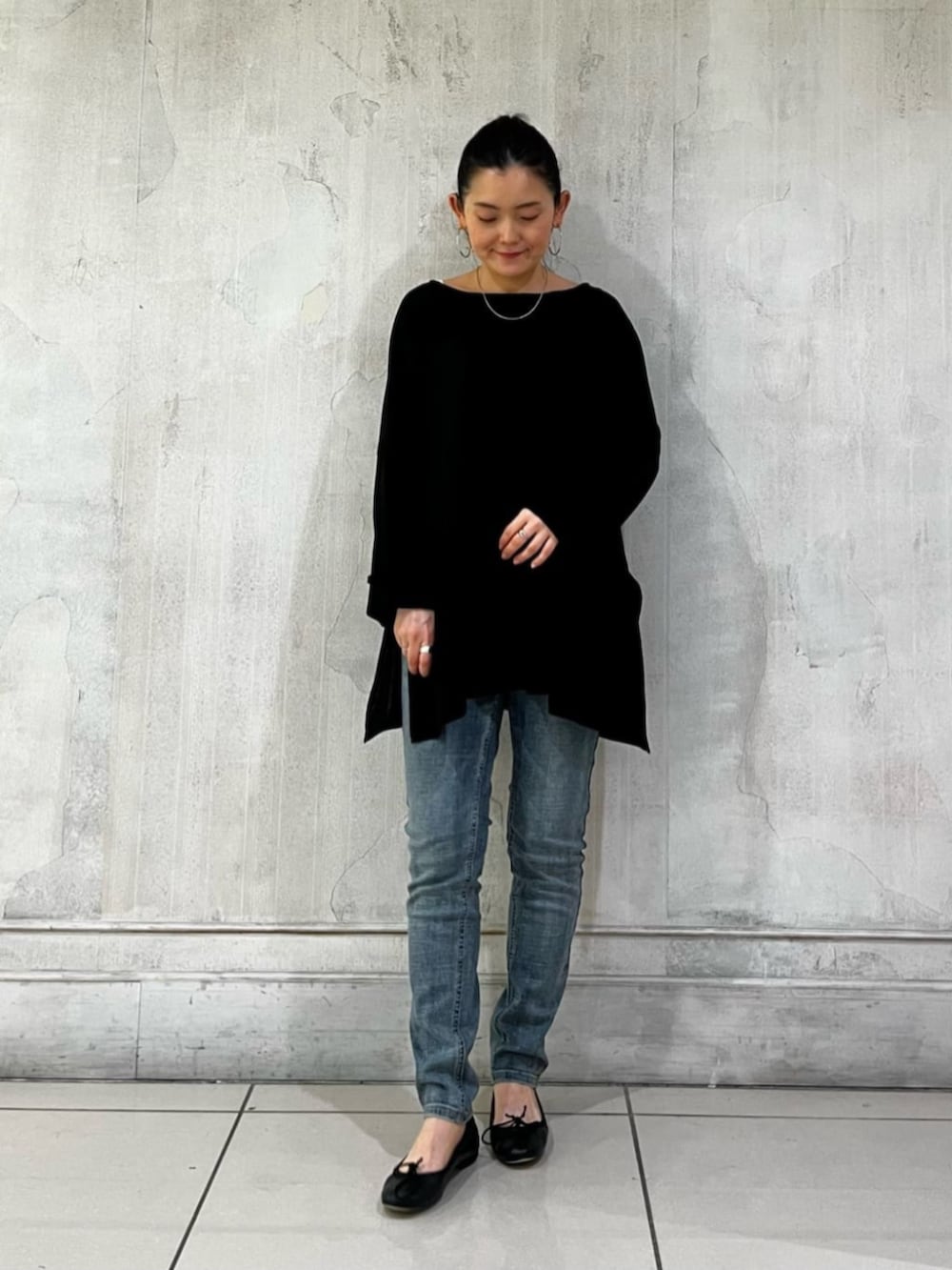 ブルー系のデニムパンツ、ブラック系のハンドバッグ、ブラック系のTシャツ/カットソーを着用したレディースの春コーディネートの2枚目の写真