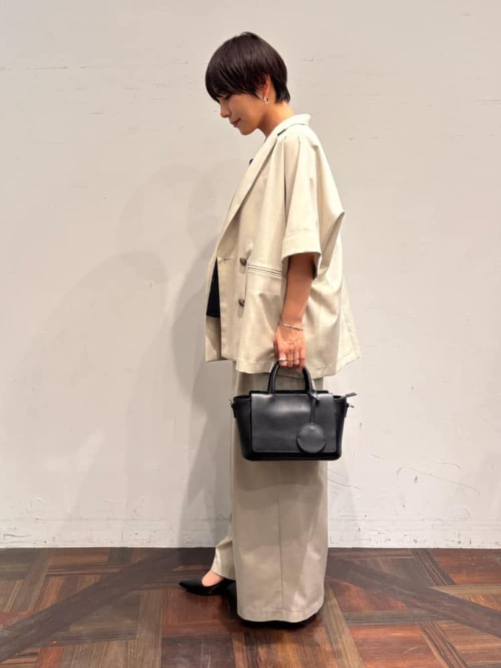 ブラック系のハンドバッグ、ベージュ系のテーラードジャケット、ベージュ系のその他パンツを着用したレディースの春コーディネートの2枚目の写真