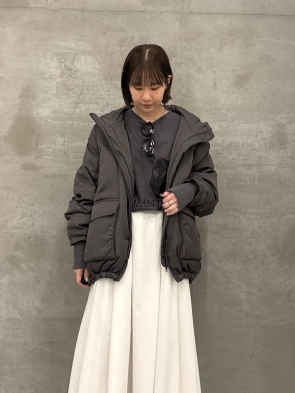 ホワイト系のスカート、グレー系のダウンジャケット/コート、グレー系のTシャツ/カットソーを着用したレディースの秋コーディネートの2枚目の写真