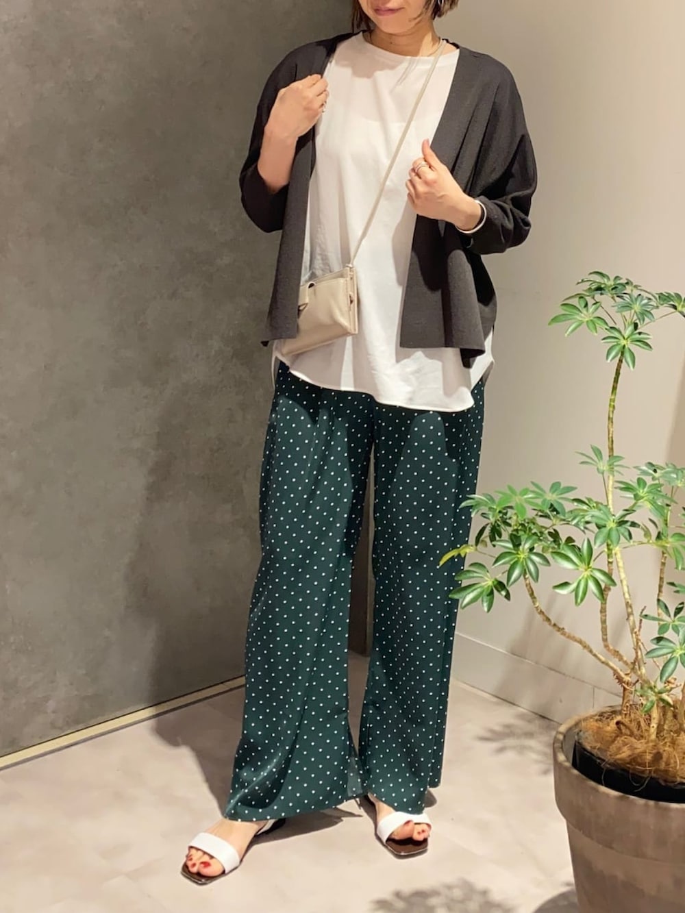 グレー系のカーディガン/ボレロ、ホワイト系のシャツ/ブラウス、グレー系のショルダーバッグを着用したレディースの夏コーディネートの2枚目の写真