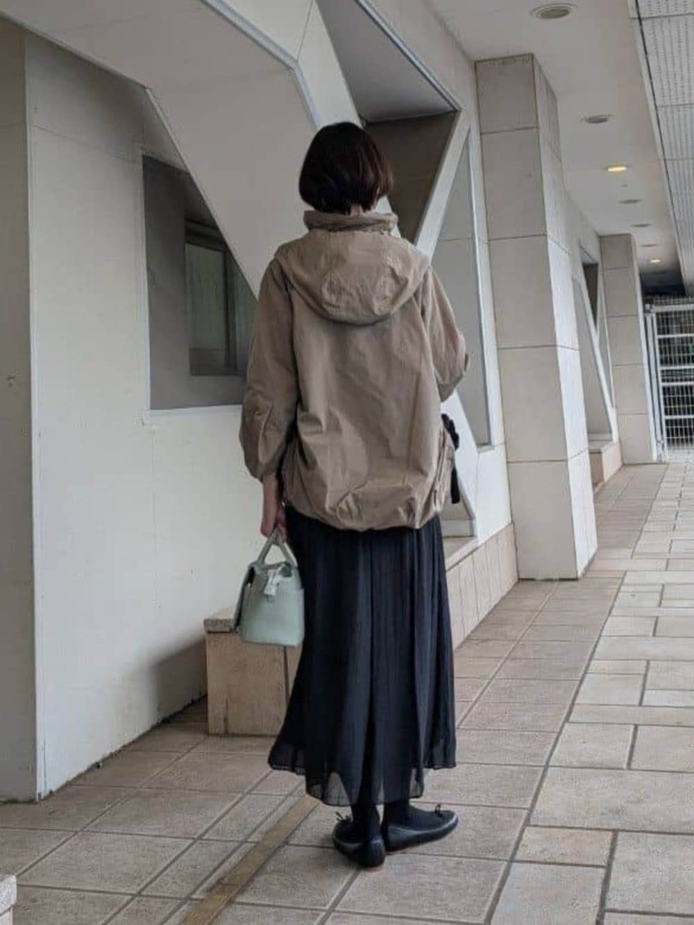 グリーン系のハンドバッグ、ブラック系のその他パンツ、ブラウン系のブルゾンを着用したレディースの冬コーディネートの3枚目の写真