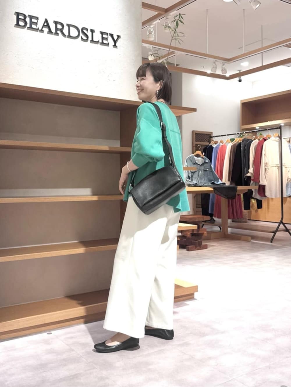 ブラック系のショルダーバッグ、ホワイト系のその他パンツ、グリーン系のTシャツ/カットソーを着用したレディースの春コーディネートの2枚目の写真