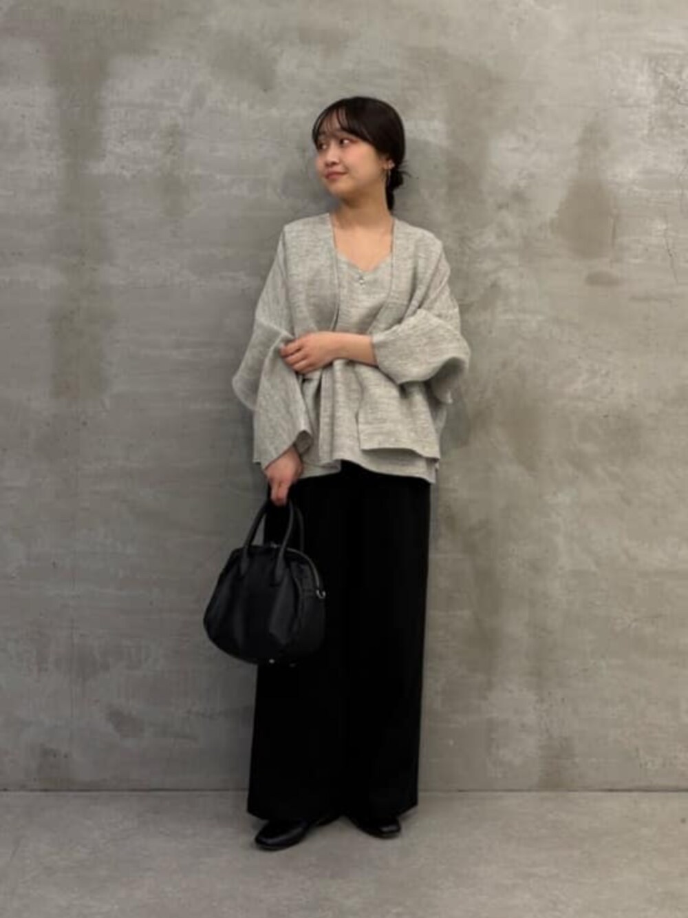 ブラック系のボストンバッグ、グレー系のニット/セーター、グレー系のカーディガン/ボレロを着用したレディースの春コーディネートの3枚目の写真
