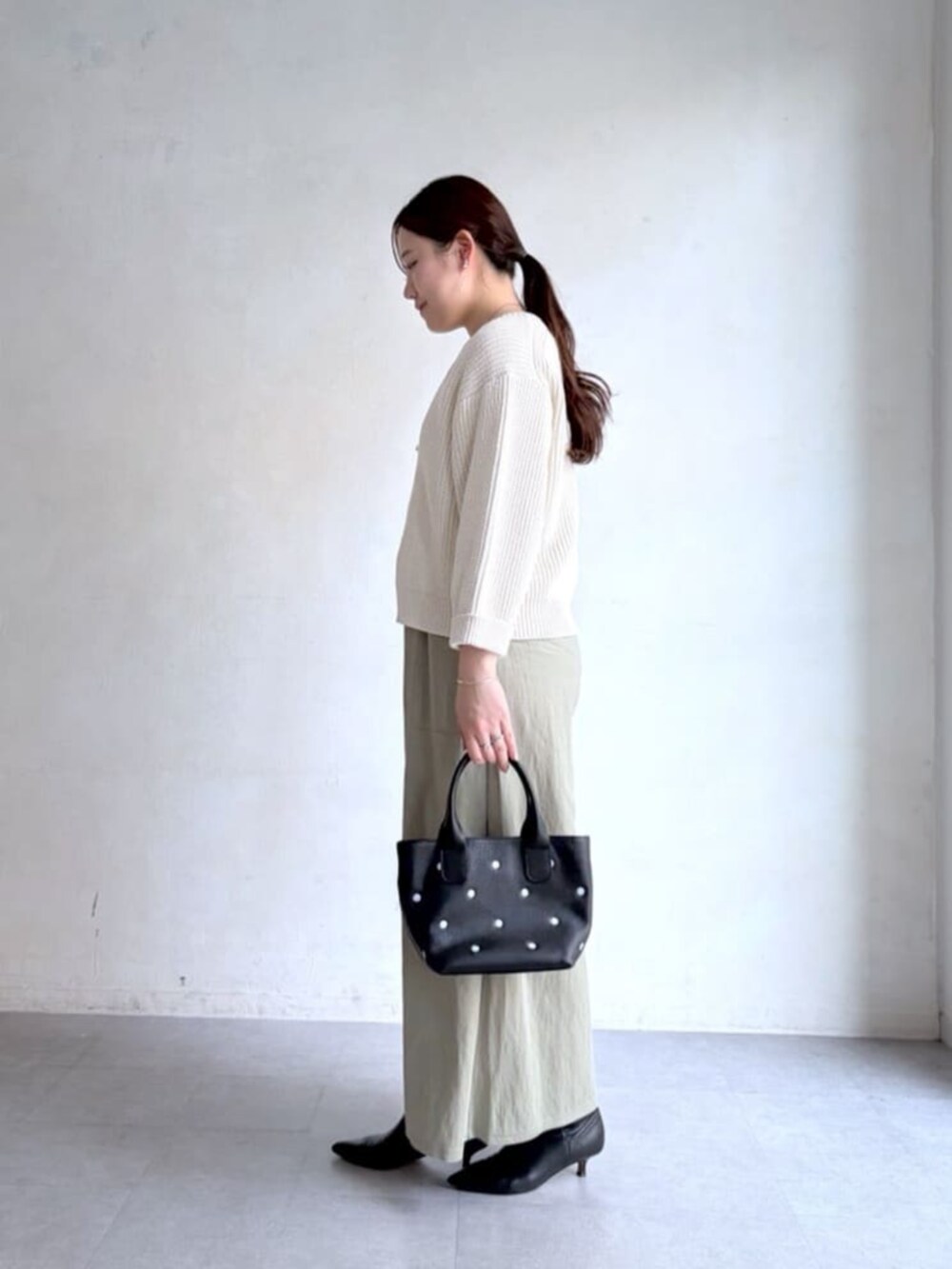 ホワイト系のニット/セーター、グリーン系のその他パンツ、ブラック系のトートバッグを着用したレディースの冬コーディネートの2枚目の写真