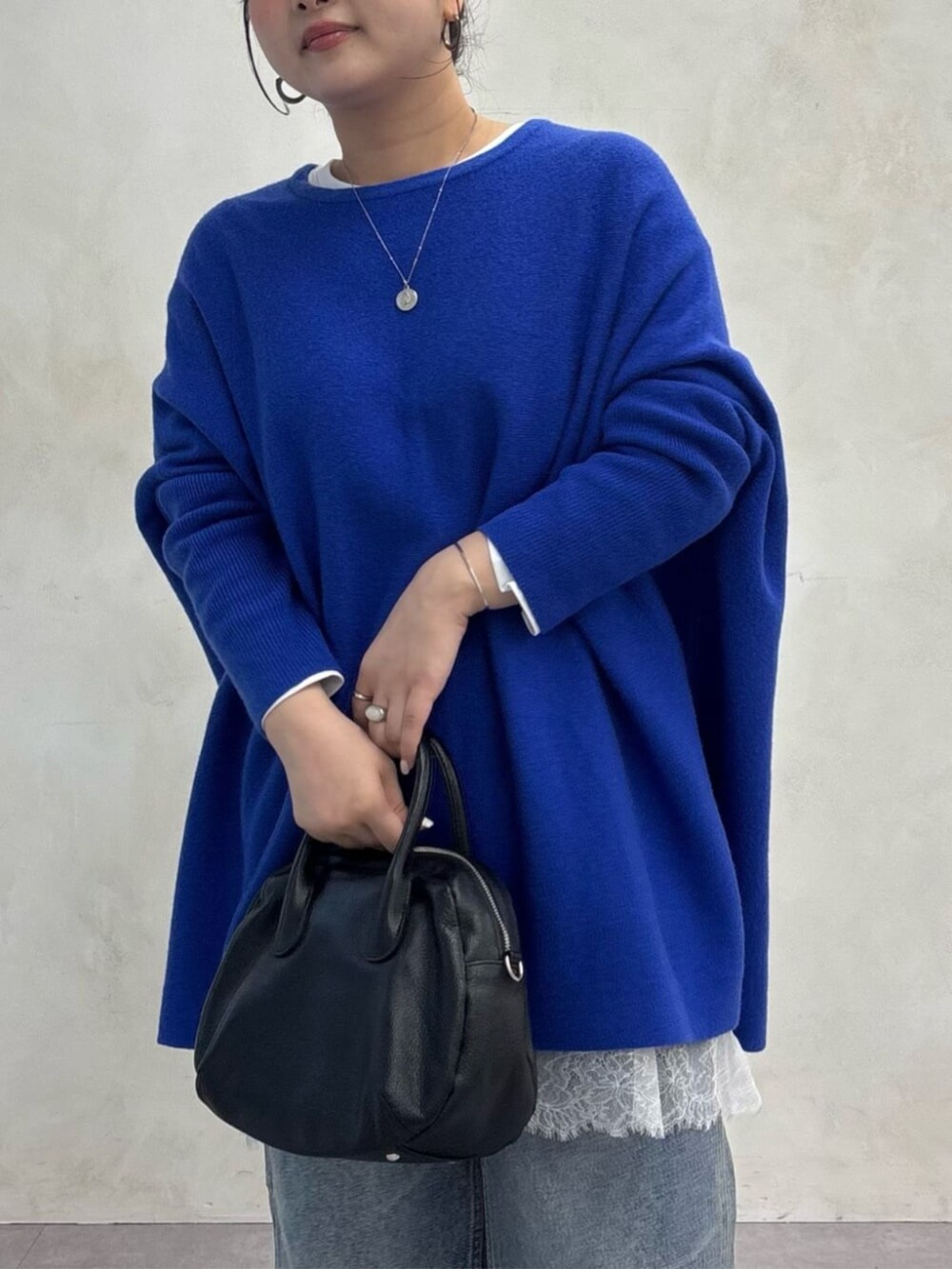ブラック系のトートバッグ、ブルー系のデニムパンツ、ブラック系のブーツを着用したレディースの秋コーディネートの3枚目の写真