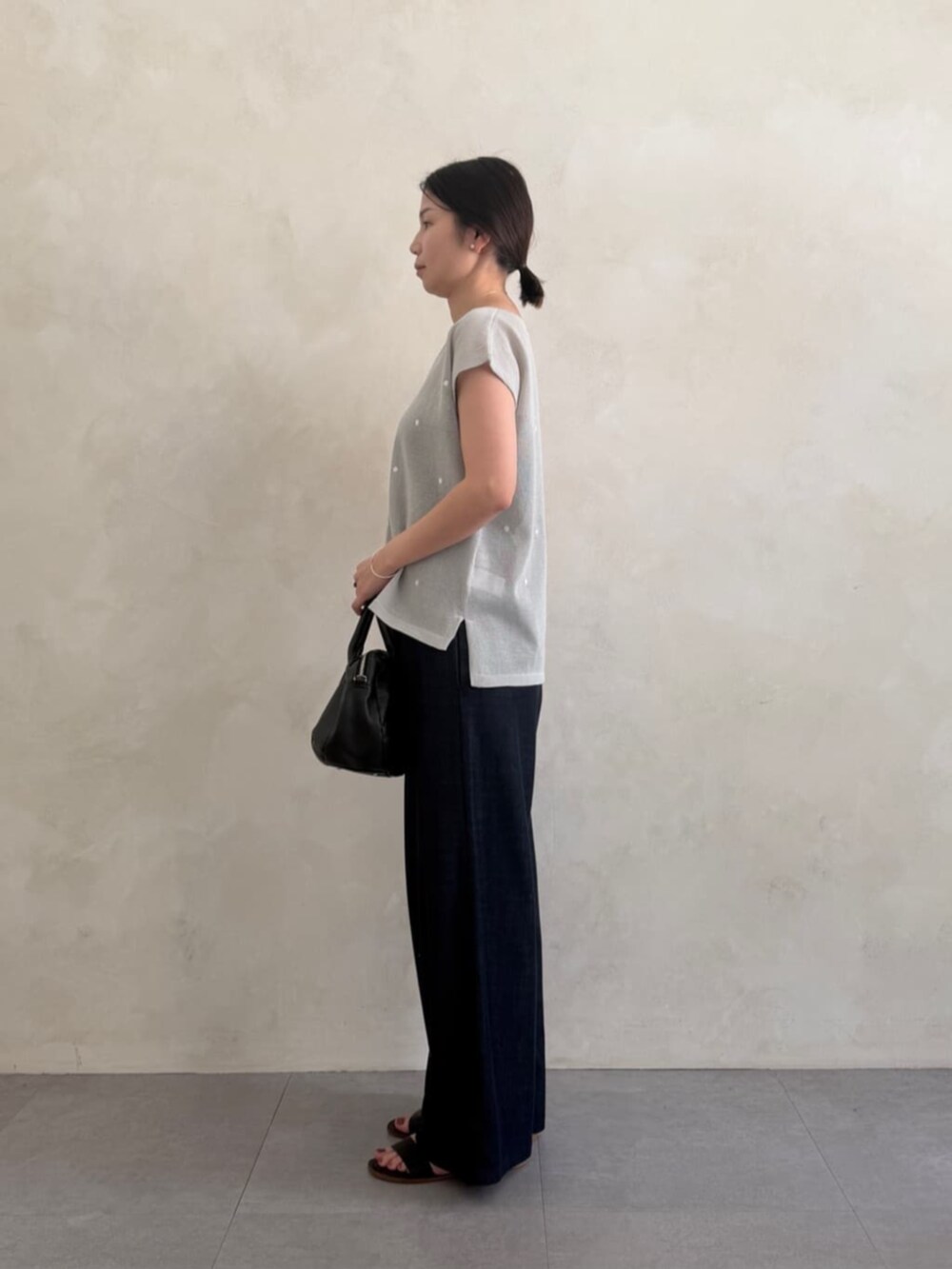 ブルー系のその他パンツ、ブラック系のボストンバッグ、グレー系のニット/セーターを着用したレディースの春コーディネートの2枚目の写真