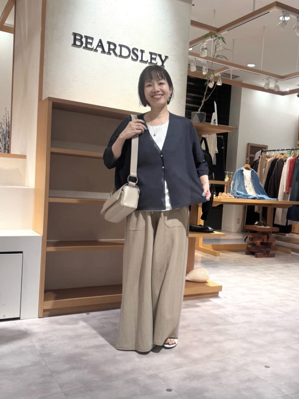 ベージュ系のその他パンツ、ベージュ系のショルダーバッグ、ブルー系のカーディガン/ボレロを着用したレディースの春コーディネートの10枚目の写真