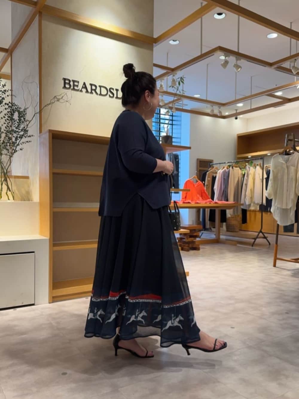 ホワイト系のトートバッグ、ブルー系のカーディガン/ボレロ、ブルー系のスカートを着用したレディースの春コーディネートの3枚目の写真