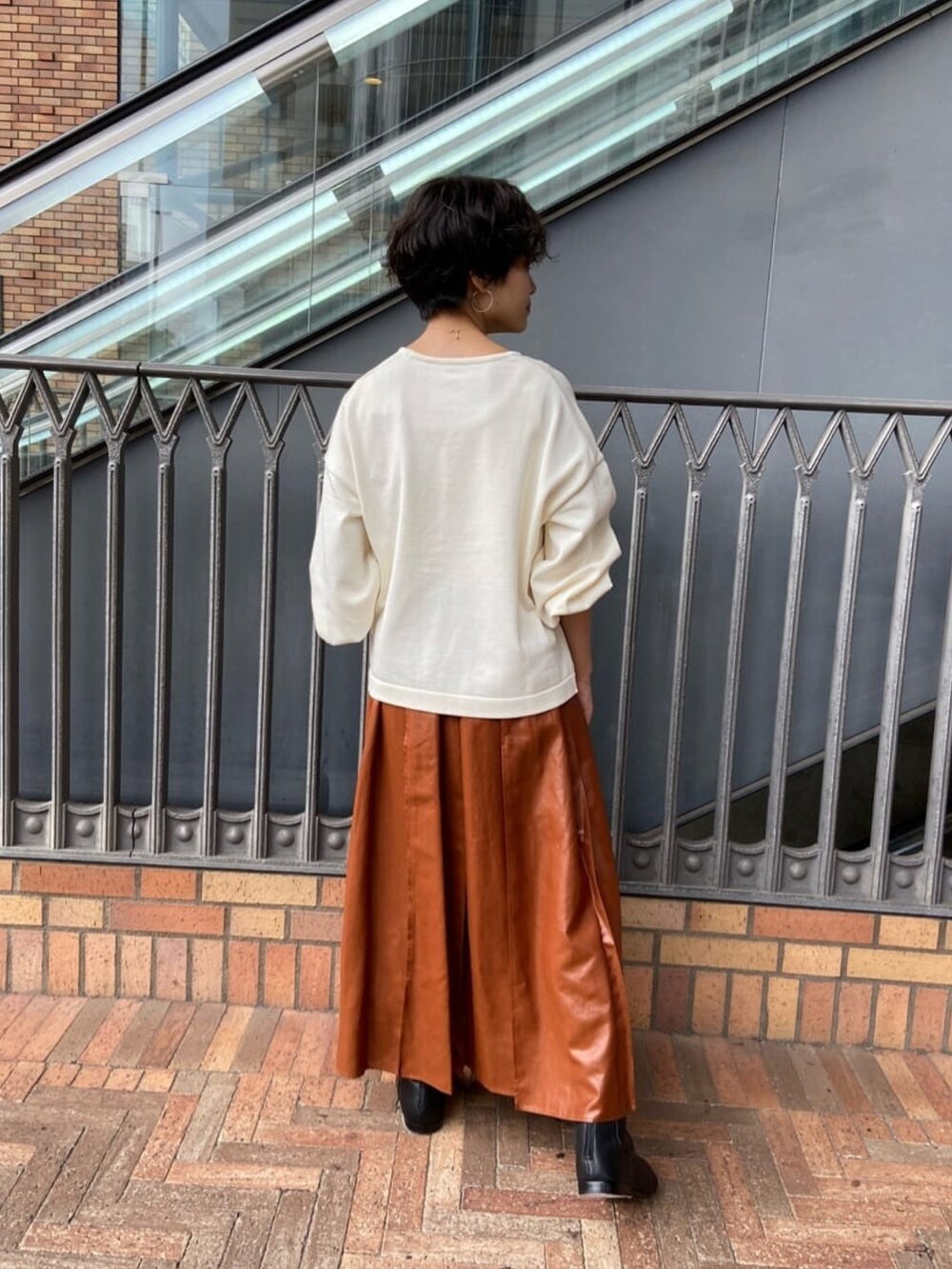 ホワイト系のニット/セーター、イエロー系のスカート、ブラック系のブーツを着用したレディースの秋コーディネートの3枚目の写真