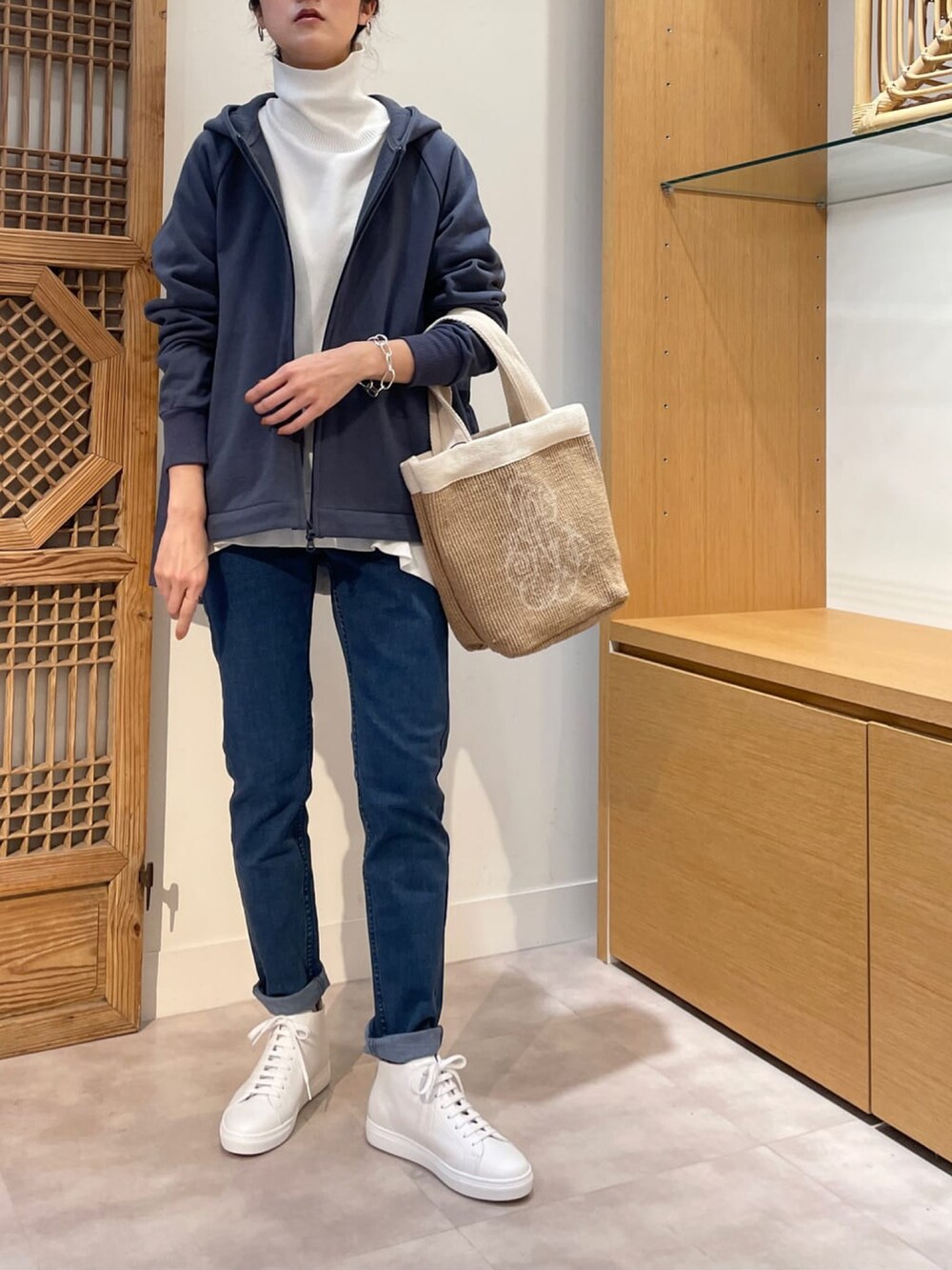 ブルー系のパーカー、ホワイト系のニット/セーター、ブルー系のデニムパンツを着用したレディースの春コーディネートの2枚目の写真