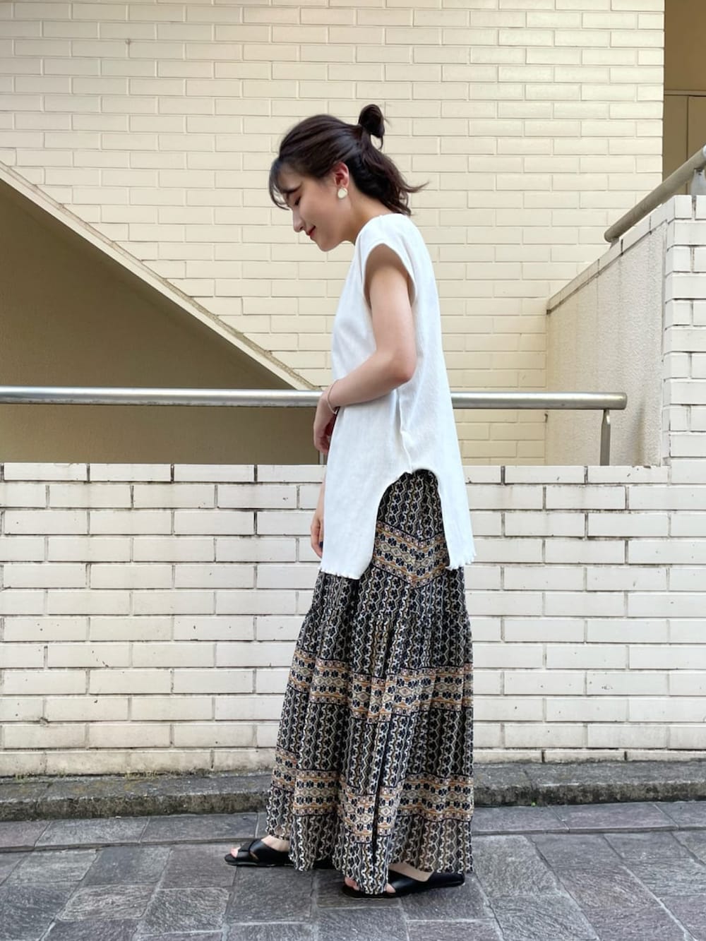 ホワイト系のTシャツ/カットソー、ブラック系のスカート、ブラック系のサンダルを着用したレディースの夏コーディネートの2枚目の写真