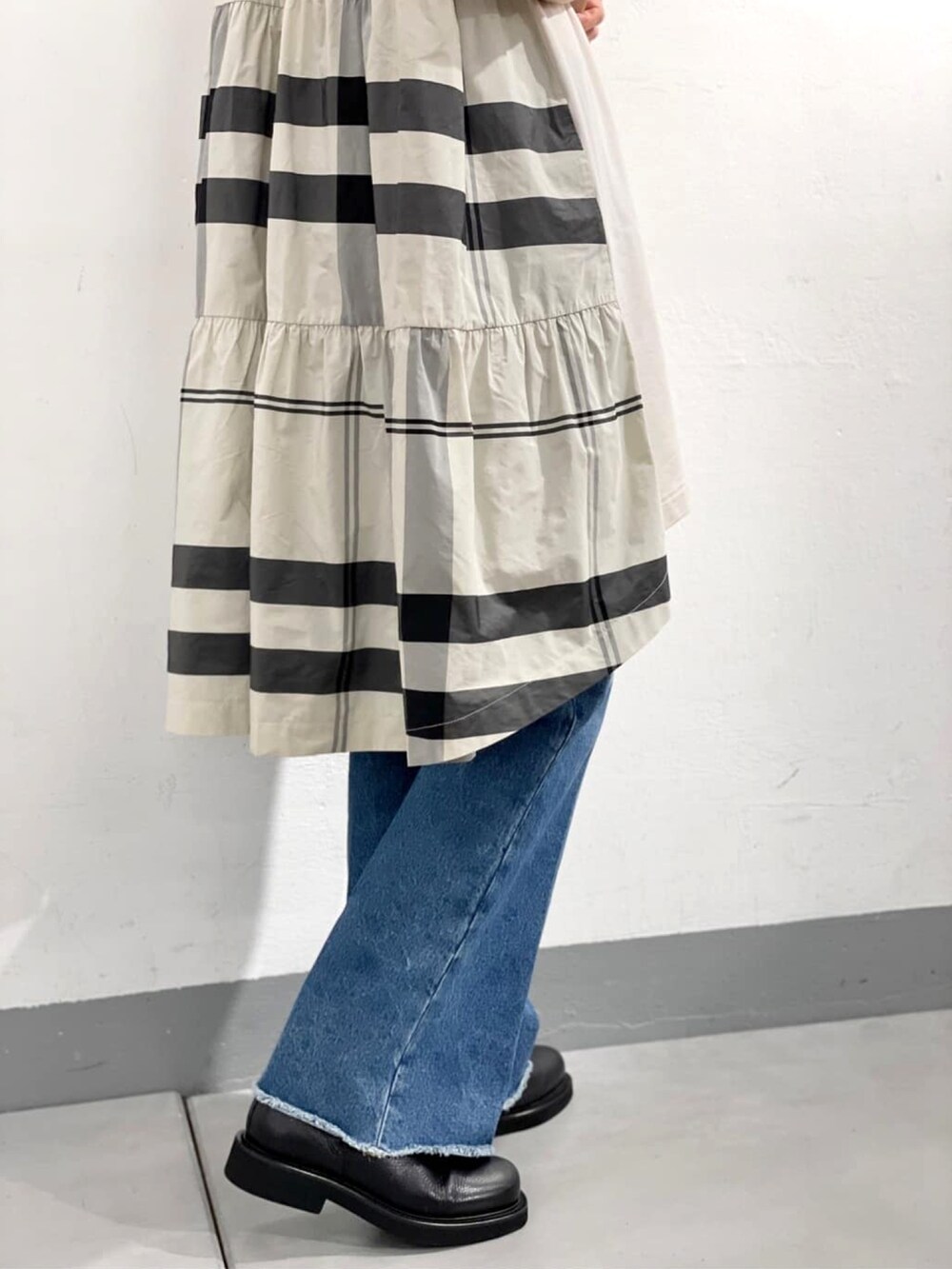 ホワイト系のワンピース、ホワイト系のショルダーバッグ、ブルー系のデニムパンツを着用したレディースの秋コーディネートの3枚目の写真