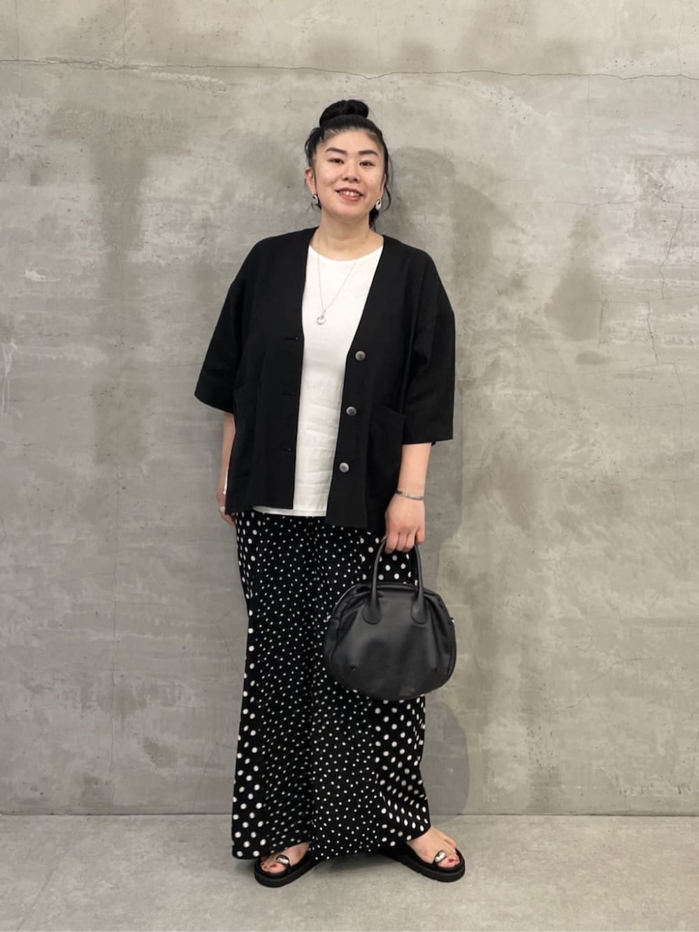 ホワイト系のタンクトップ、ブラック系のボストンバッグ、ブラック系のサンダルを着用したレディースの春コーディネートの2枚目の写真