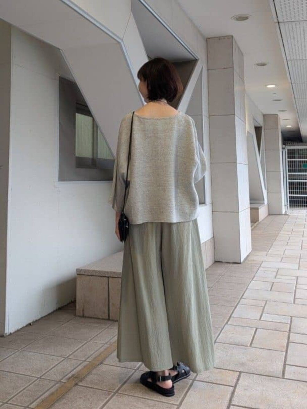 グリーン系のその他パンツ、グレー系のニット/セーター、ブラック系のサンダルを着用したレディースの冬コーディネートの3枚目の写真