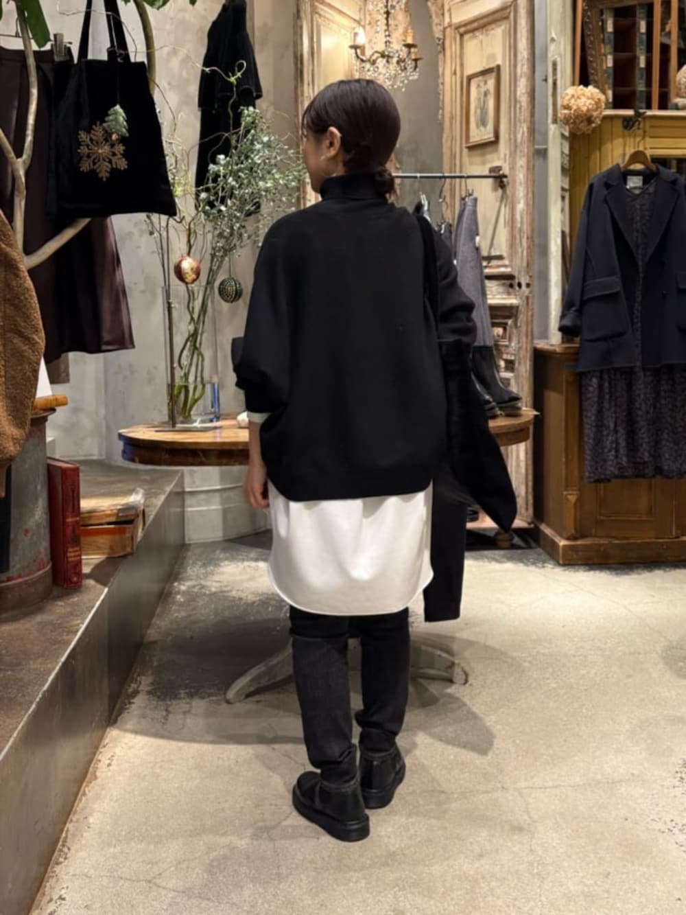 ブラック系のニット/セーター、ブラック系のデニムパンツ、ホワイト系のシャツ/ブラウスを着用したレディースの冬コーディネートの3枚目の写真