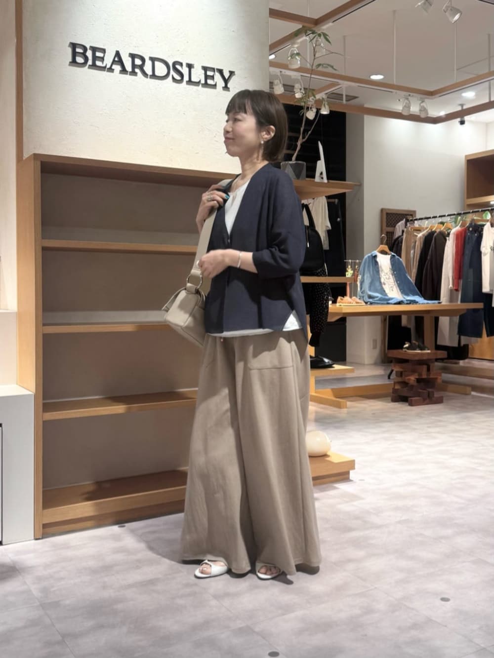 ベージュ系のその他パンツ、ベージュ系のショルダーバッグ、ブルー系のカーディガン/ボレロを着用したレディースの春コーディネートの5枚目の写真