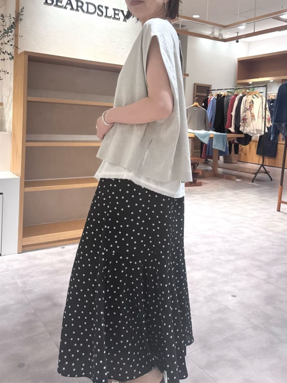 ブラック系のハンドバッグ、ブラック系のスカート、ベージュ系のシャツ/ブラウスを着用したレディースの春コーディネートの7枚目の写真