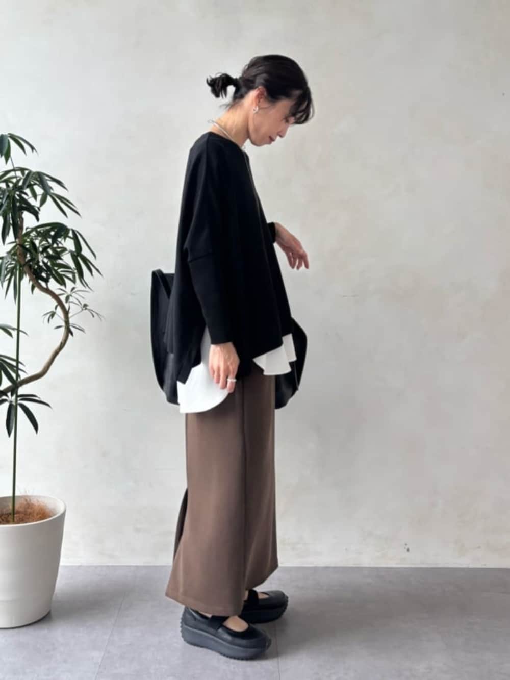 ブラック系のスニーカー、ブラウン系のスカート、ブラック系のニット/セーターを着用したレディースの夏コーディネートの2枚目の写真
