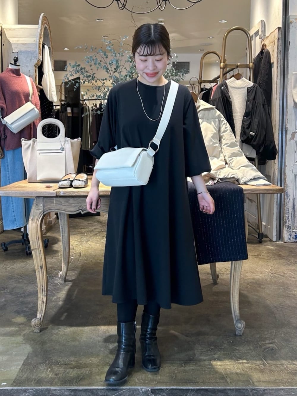 ホワイト系のショルダーバッグ、ブラック系のワンピースを着用したレディースの冬コーディネートの2枚目の写真