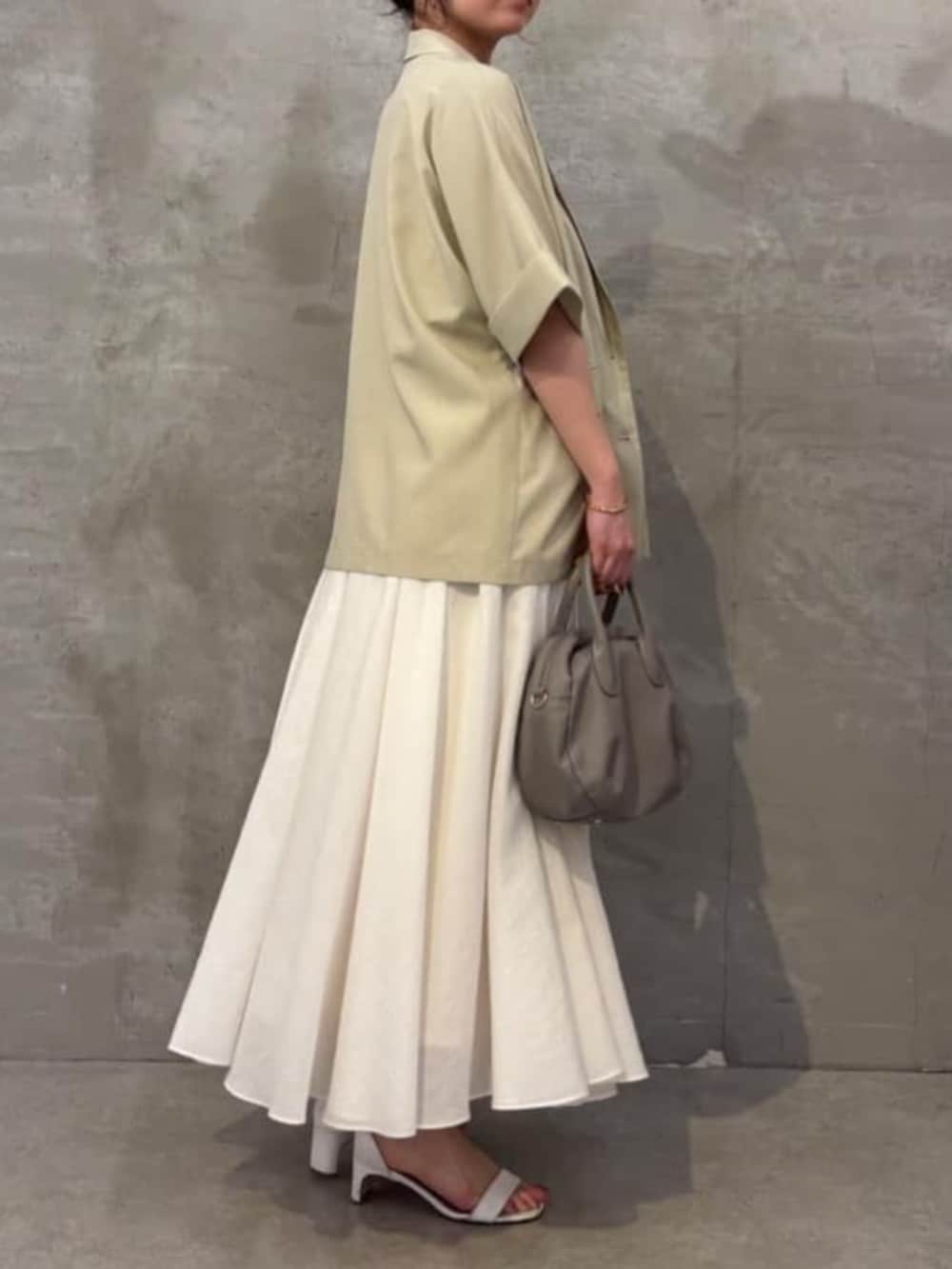 グレー系のボストンバッグ、ホワイト系のキャミソール、ベージュ系のテーラードジャケットを着用したレディースの春コーディネートの2枚目の写真