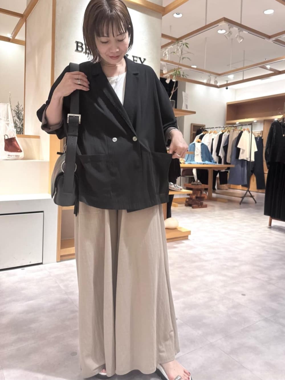 ブラック系のテーラードジャケット、ベージュ系のその他パンツ、ホワイト系のサンダルを着用したレディースの春コーディネートの2枚目の写真
