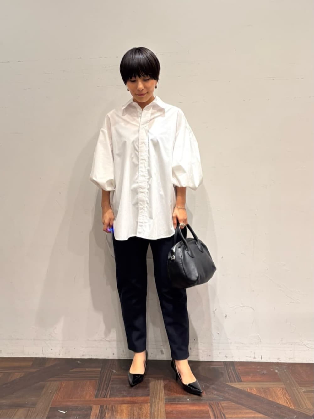 ブラック系のボストンバッグ、ブルー系のベスト、ホワイト系のシャツ/ブラウスを着用したレディースの冬コーディネートの9枚目の写真