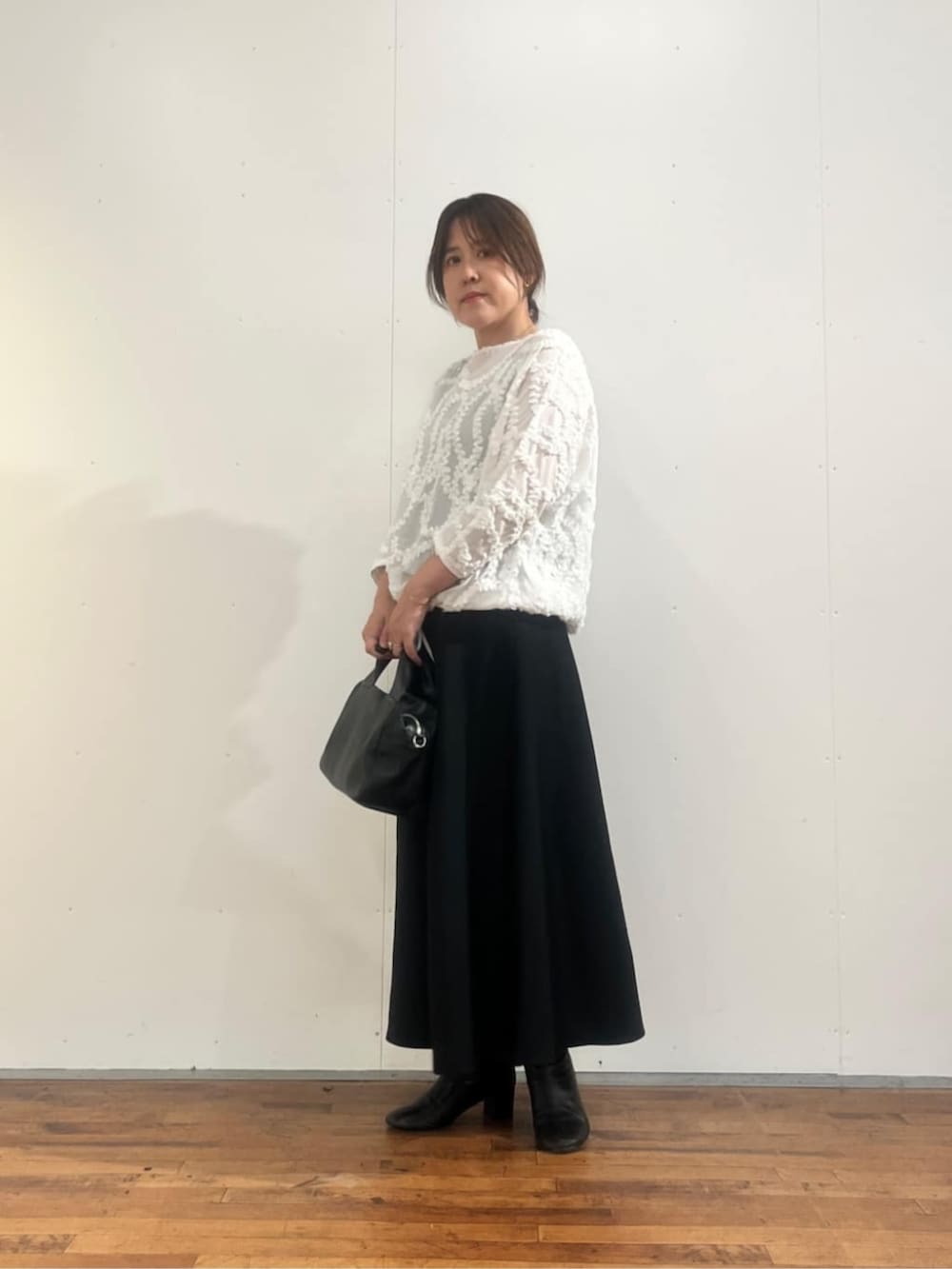 ブラック系のボストンバッグ、ブラック系のスカート、ホワイト系のシャツ/ブラウスを着用したレディースの夏コーディネートの2枚目の写真
