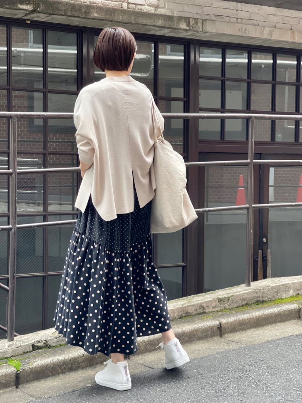 ベージュ系のカーディガン/ボレロ、ブラック系のワンピース、ホワイト系のスニーカーを着用したレディースの春コーディネートの3枚目の写真