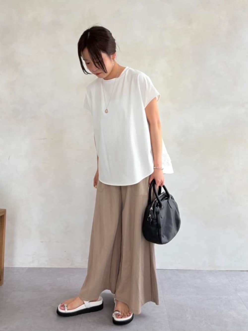 ベージュ系のその他パンツ、ホワイト系のサンダル、ホワイト系のTシャツ/カットソーを着用したレディースの春コーディネートの2枚目の写真