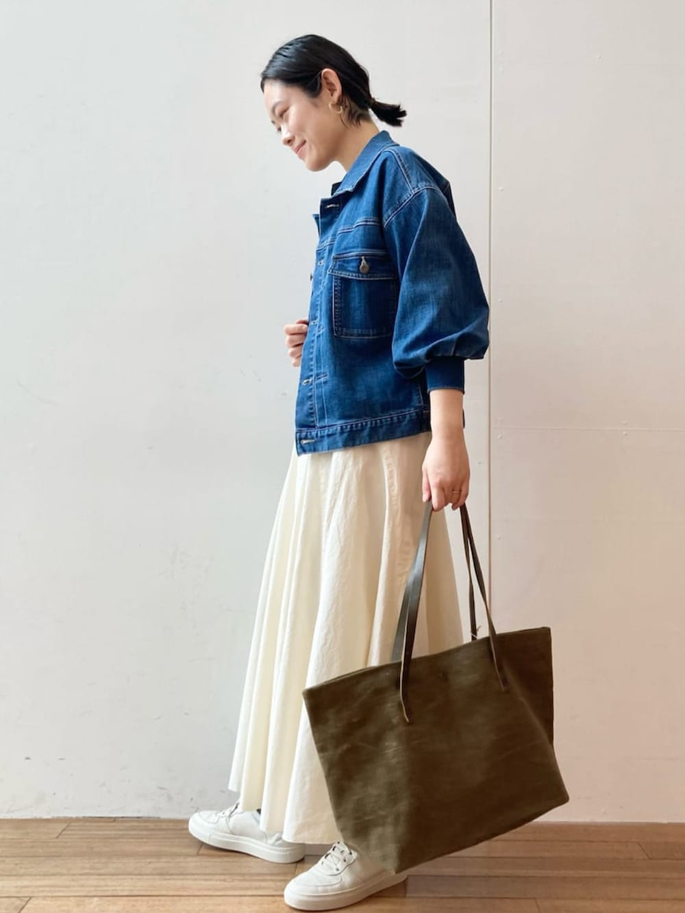 ブルー系のデニムジャケット、ブラック系のTシャツ/カットソー、ホワイト系のスカートを着用したレディースの冬コーディネートの2枚目の写真